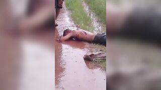 Mangled Man Convulses in Agonizing Pain, Covered in Machete Wounds and Filthy Mud
