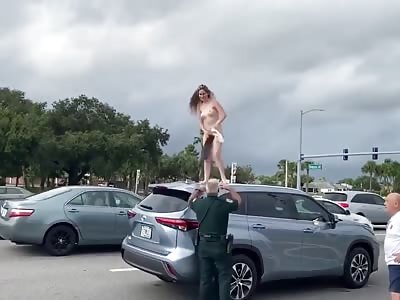 Naked chick dances on top of car.