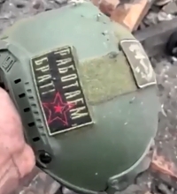 Ukrainian soldier shows a Russian helmet with a bullet hole...