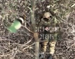 A grenade is dropped on a Russian soldier lying on his back
