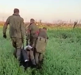 Russian POWs carry a dead comrade under UAF watch