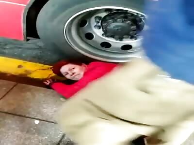 Woman has her arm caught in a back wheel of a bus.