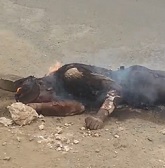 Charred Dude Burns on the Street as People Drive and Walk By