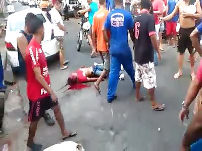 BLOODIED MAN LYING IN THE GROUND SURROUNDED BY MOB