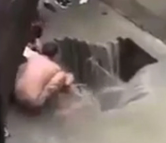 MAN BEING  SWALLOWED BY A HOLE IN THE FLOODING