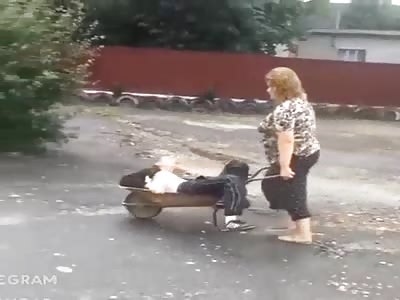 Russian woman carrying her drunk husband to home 