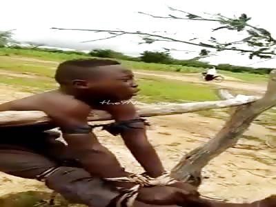 African boy tied to a wooden post.