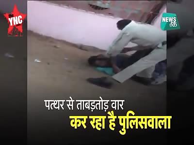A drunk man is being  beaten with a stone and a pipe by a policeman in  Madhya Pradesh