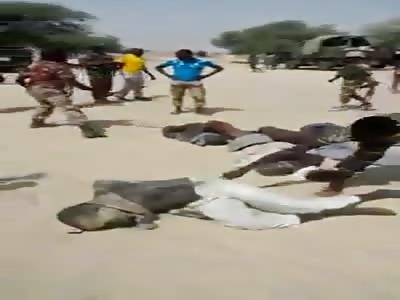 Captives in the sand are surrounded by the army as villagers hack at t