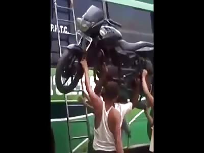 Indian supeman carries a motorbike on his head while climbing a ladder