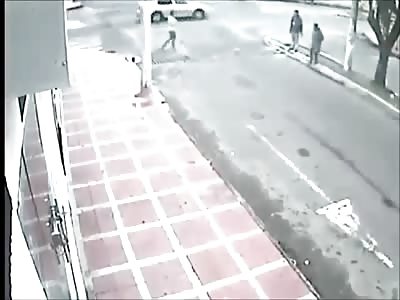 Two people waiting to cross the street get taken out by a truck